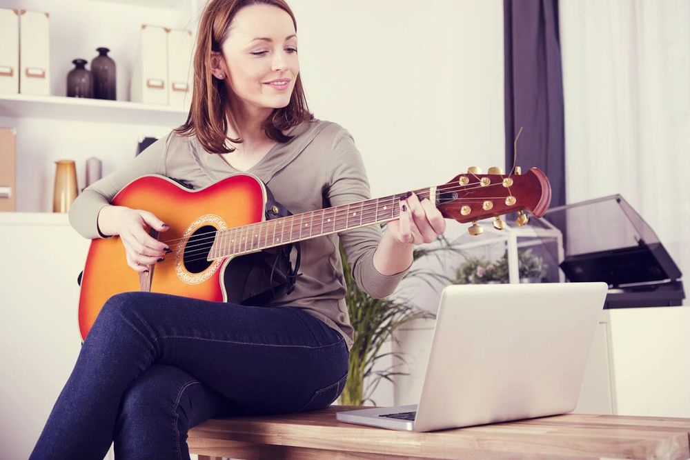 Junge Frau spielt Gitarre und gibt dies als Hobby im Lebenslauf an.
